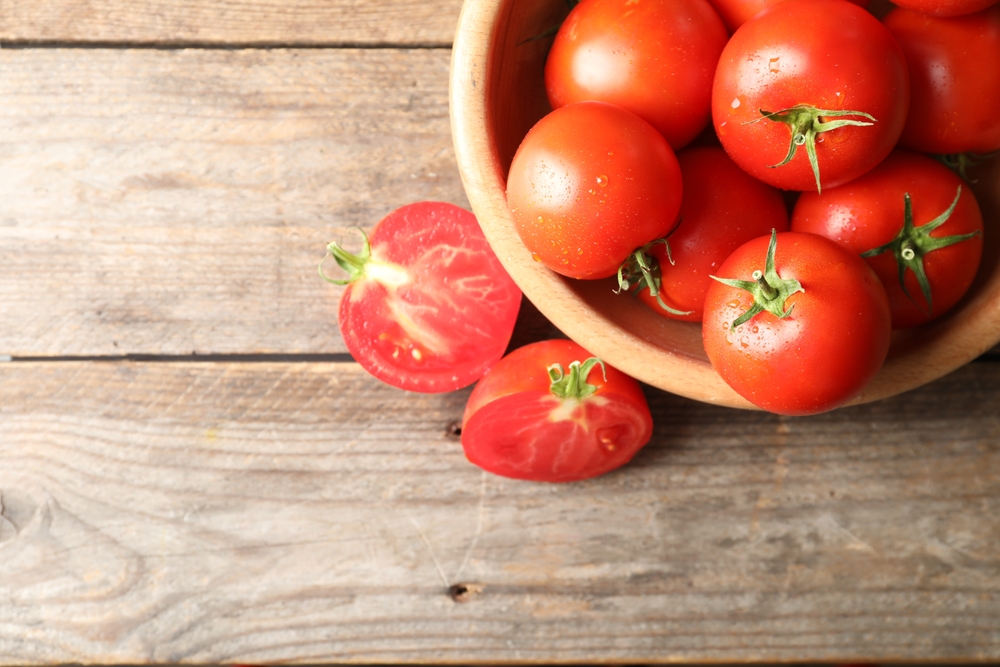 FreshRipeTomatoesOnWoodenTableFlatLaySpaceFor - USA Works Red tomatoes in a wooden bowl on a rustic wooden table, to reference tomato prices