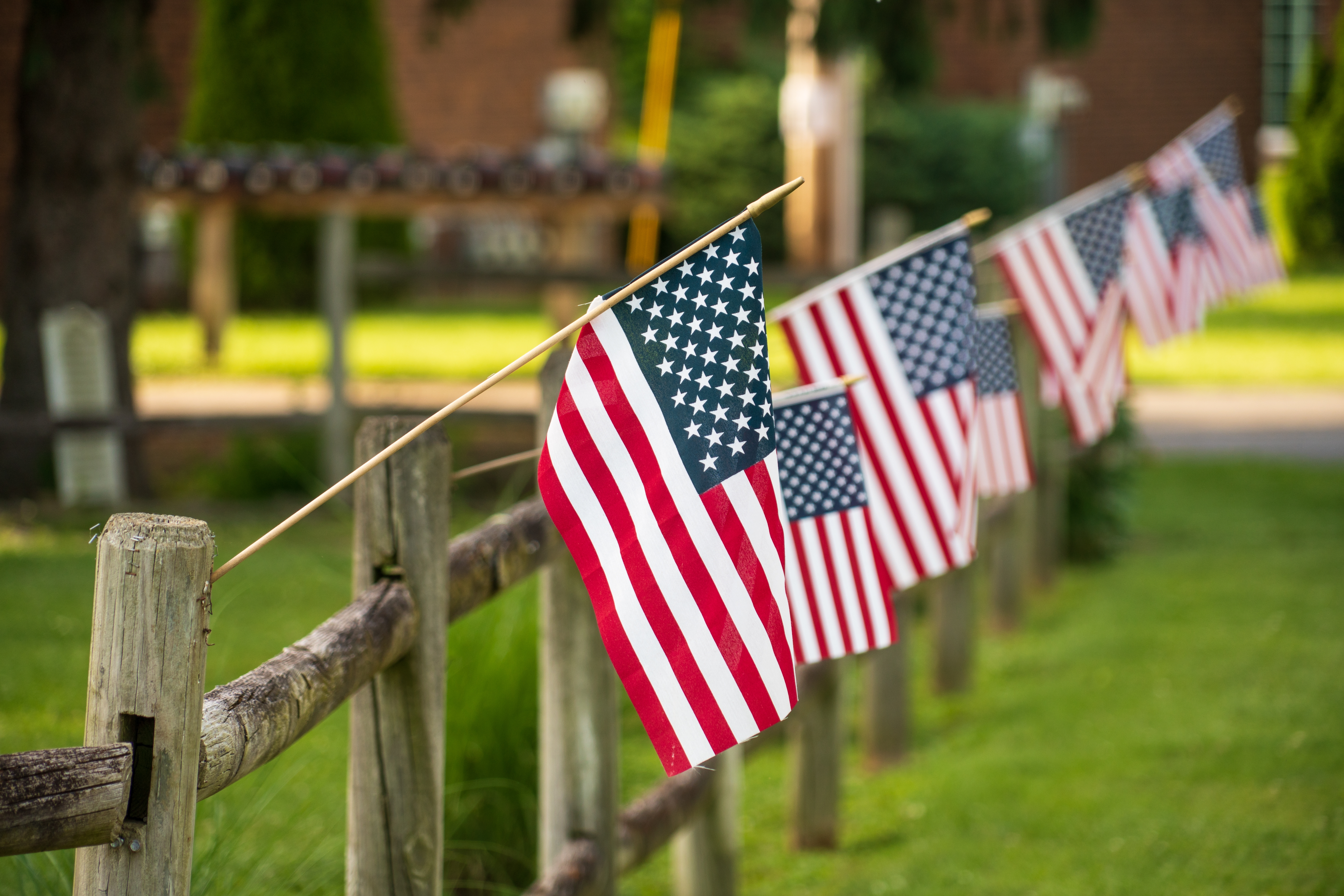 RuralAmericaAmericanFlagsOnAFenceSomewhereInRural - USA Works American flags are posted out of a fence.