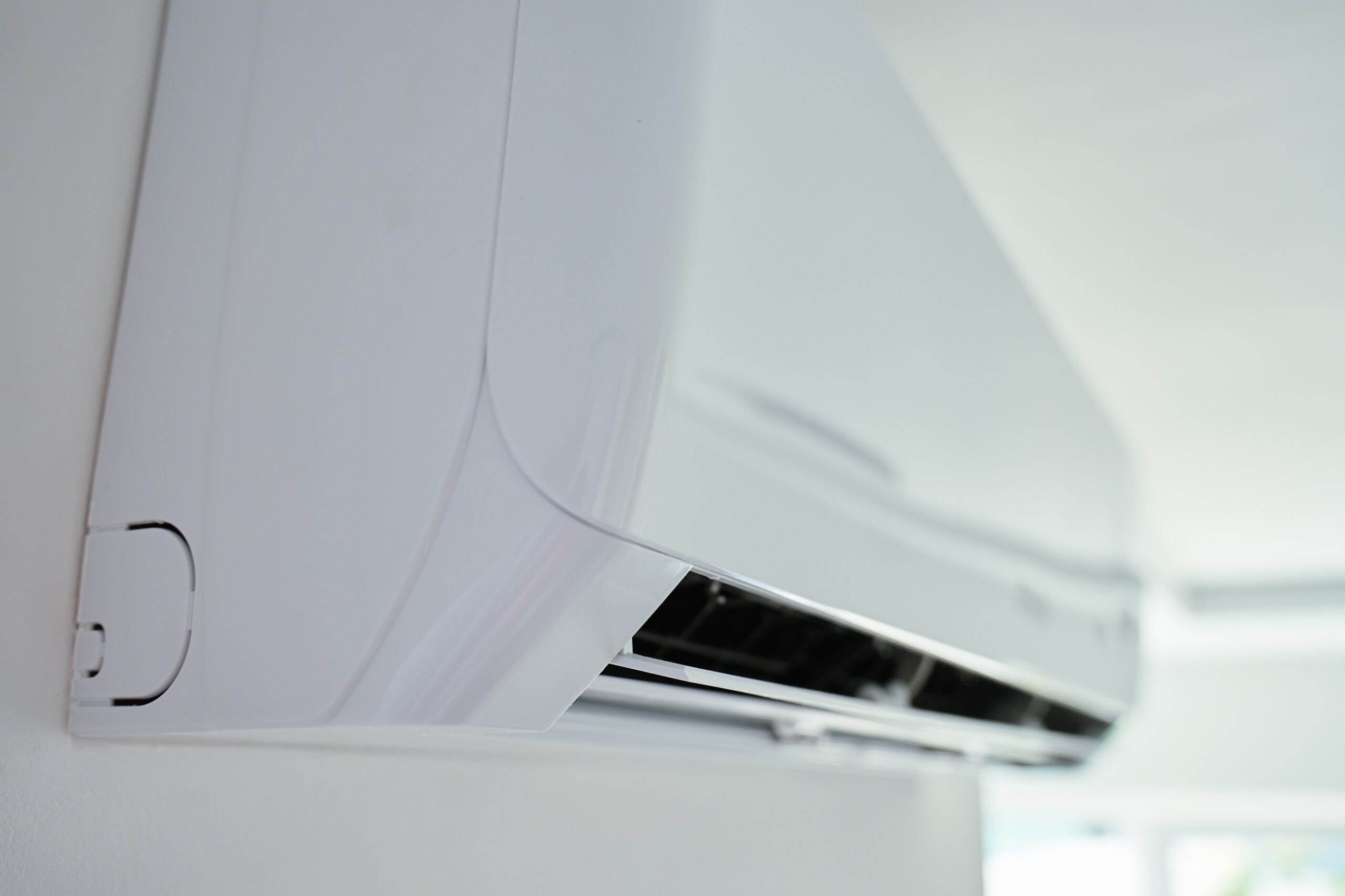 Close-up of a white wall-mounted appliance panel with a curved edge and vent area visible at the bottom right side of the image