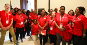Group of nurses in red scrubs outside congressional office