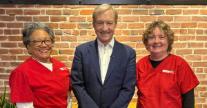 Two nurse leaders posing, smiling with Tom Steyer
