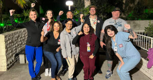 Group of nurses outside, at night, smiling, with raised fists