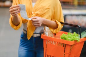 WomanHoldingAShoppingReceiptInASupermarketCheckingPrices - USA Works