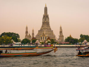 Global Economic Cooperation Jobs AI and Trade Imbalance Challenges - USA Works - USA Works Boats and tourists around Wat Arun in Bangkok.